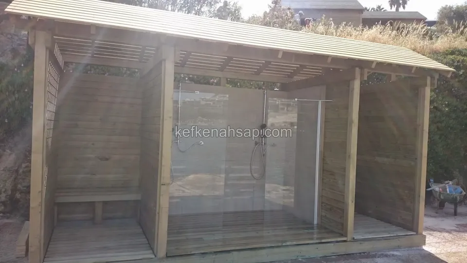 Eğik çatılı, cepheleri açık, cam bölmeli ve yan bölümde bankı bulunan ahşap dış duş kabini
