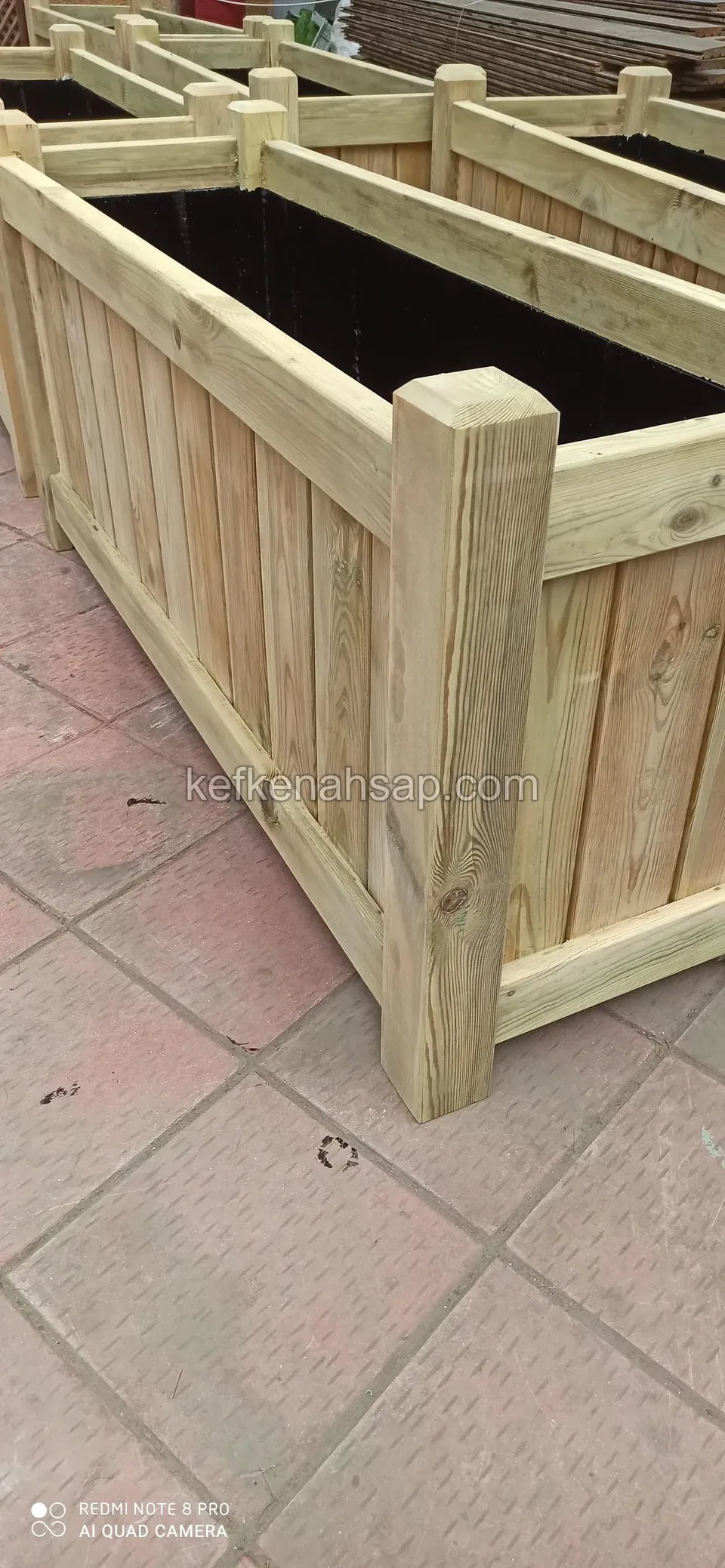 Close-up of the thick corner post and black liner of a light timber planter with vertical boards