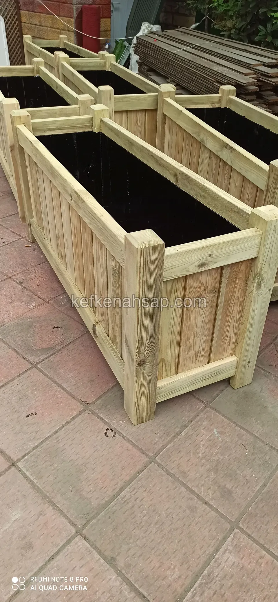 Close view of light timber planters with vertical boards and corner posts standing side by side on a tiled floor