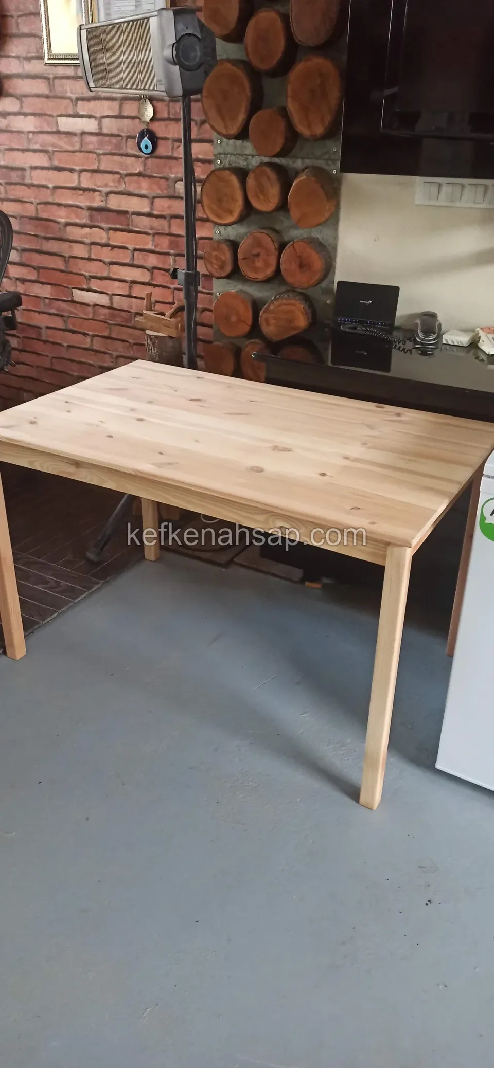 Ein heller rechteckiger Holztisch mit schlanken Beinen auf grauem Boden