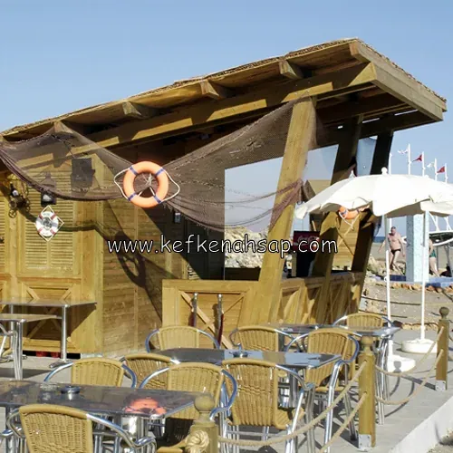 Üstü ahşap kirişli çatıyla örtülü bar yapısı; cankurtaran simidi, balık ağı süsü ve hasır sandalyeli masalar