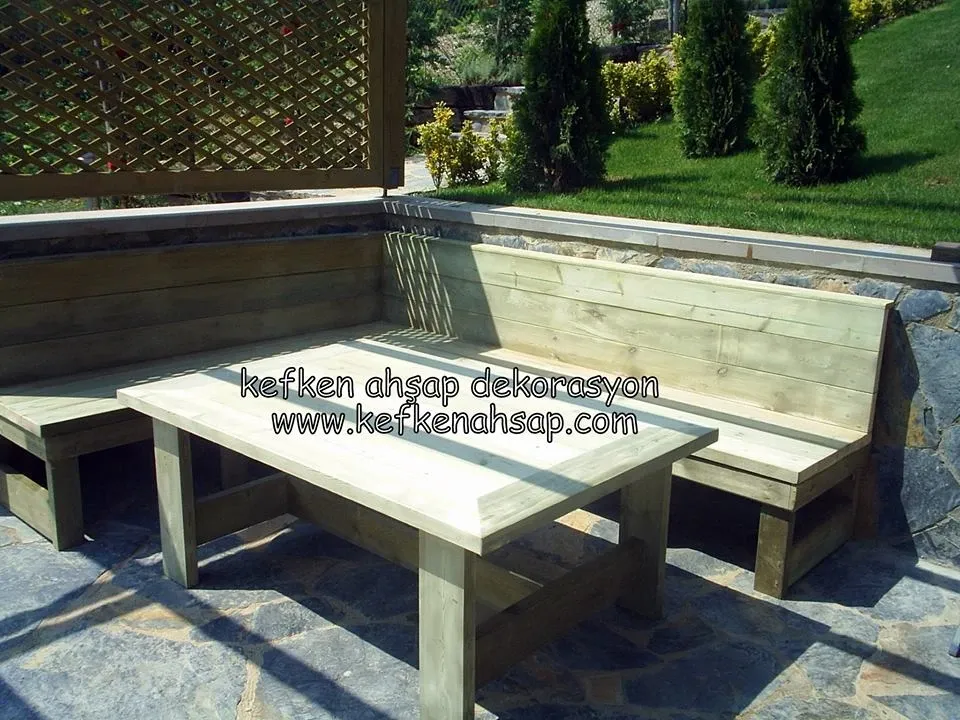 L-shaped wooden corner bench with backrest and matching outdoor table on a stone patio.