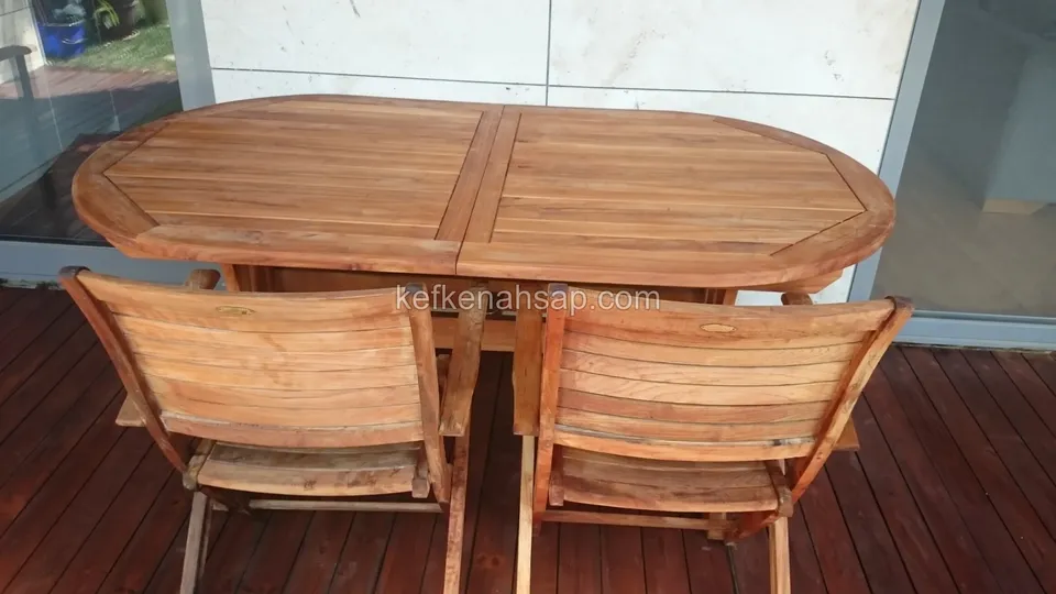 Koyu ahşap deck üzerinde oval masa ve iki katlanır ahşap sandalye