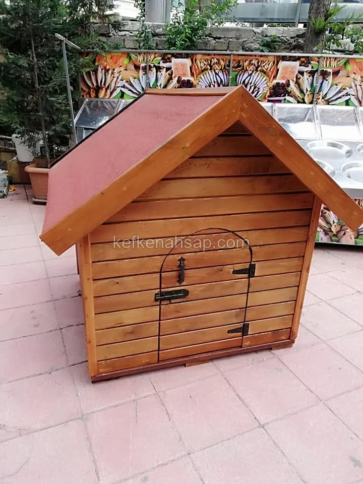 Kırmızı kaplamalı beşik çatılı, yatay tahtalı ve kemerli kapılı küçük ahşap köpek kulübesi, karo zemin üzerinde