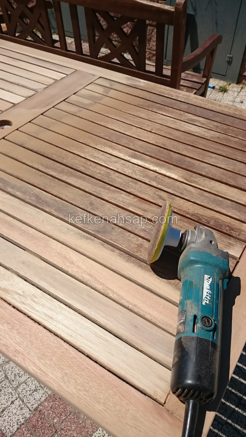 Die Lattenplatte eines Holztisches für draußen wird mit einer Schleifmaschine bearbeitet