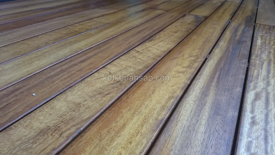 Alçak açıdan çekilmiş, sarıdan kahveye dalgalı damarlı ve ışığı yansıtan deck tahtaları