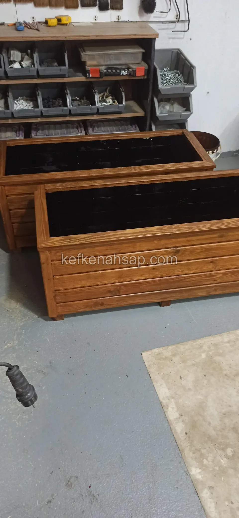 Long varnished timber planters side by side in the workshop, with a rack of screw and nail boxes behind
