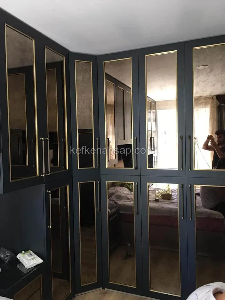 خزانة ملابس ركنية فحمية في غرفة نوم بأبواب مرايا بقضبان نحاسية ومقابض معدنية