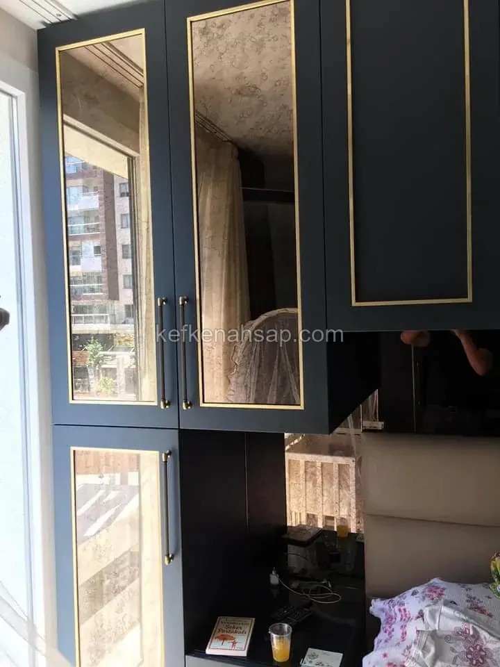 وحدة خزانة بأبواب لاكيه داكنة بمرايا برونزية وقضبان بإطار نحاسي بجانب رأس السرير
