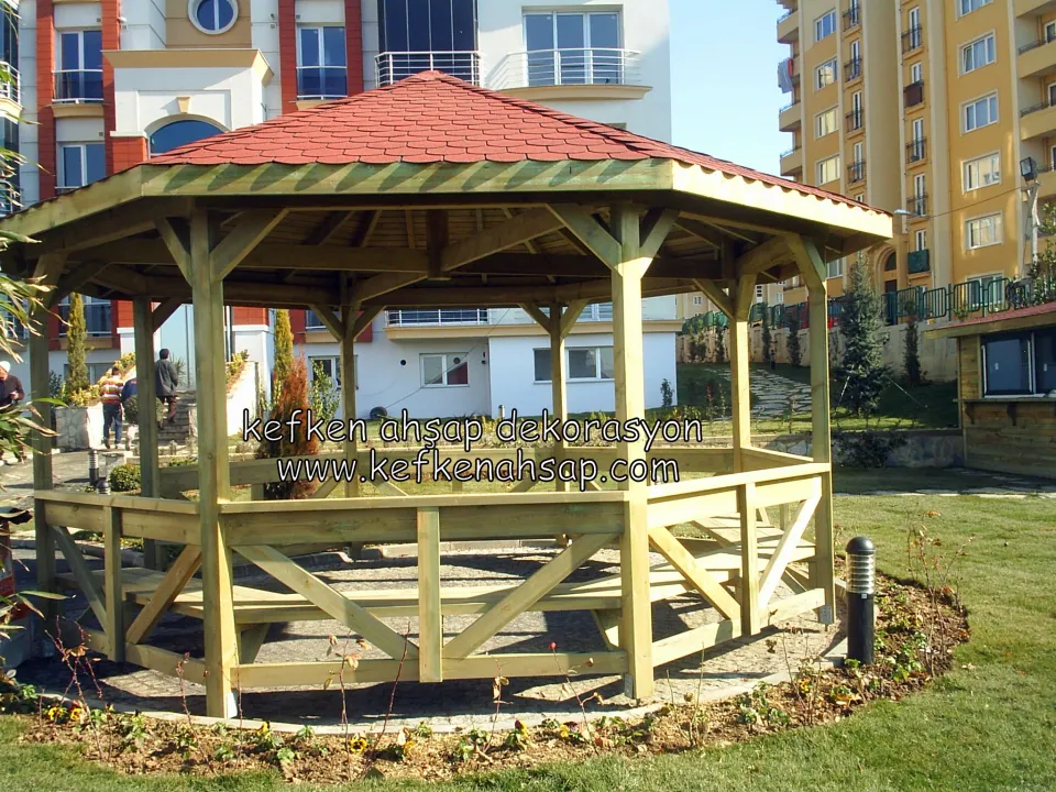 Site bahçesinde kırmızı şıngıl çatılı, ahşap korkuluklu ve oturma banklı sekizgen kamelya.