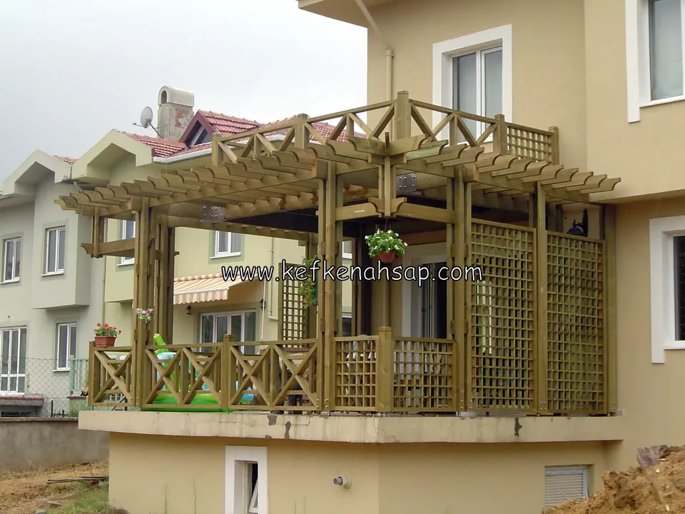 Bej cepheli evin balkonunda çapraz korkuluklu, kafes panelli ve üstü kirişli ahşap pergola