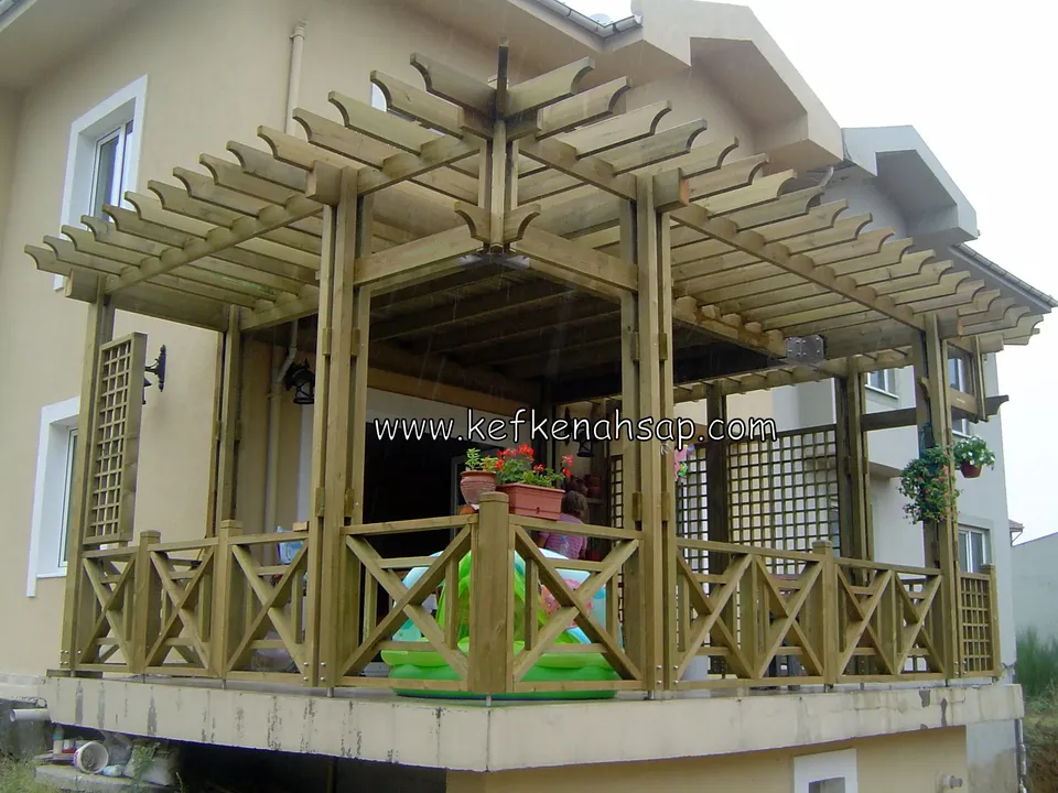 Balkonun üzerine kurulu ahşap pergola, yan kafes panel, çapraz çıtalı korkuluk ve sıralı saksılar