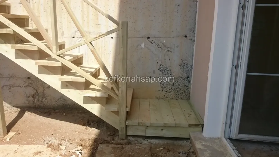Beton duvar önünde çaprazlı ahşap merdiven; cam kapının önünde küçük bir ahşap sahanlık