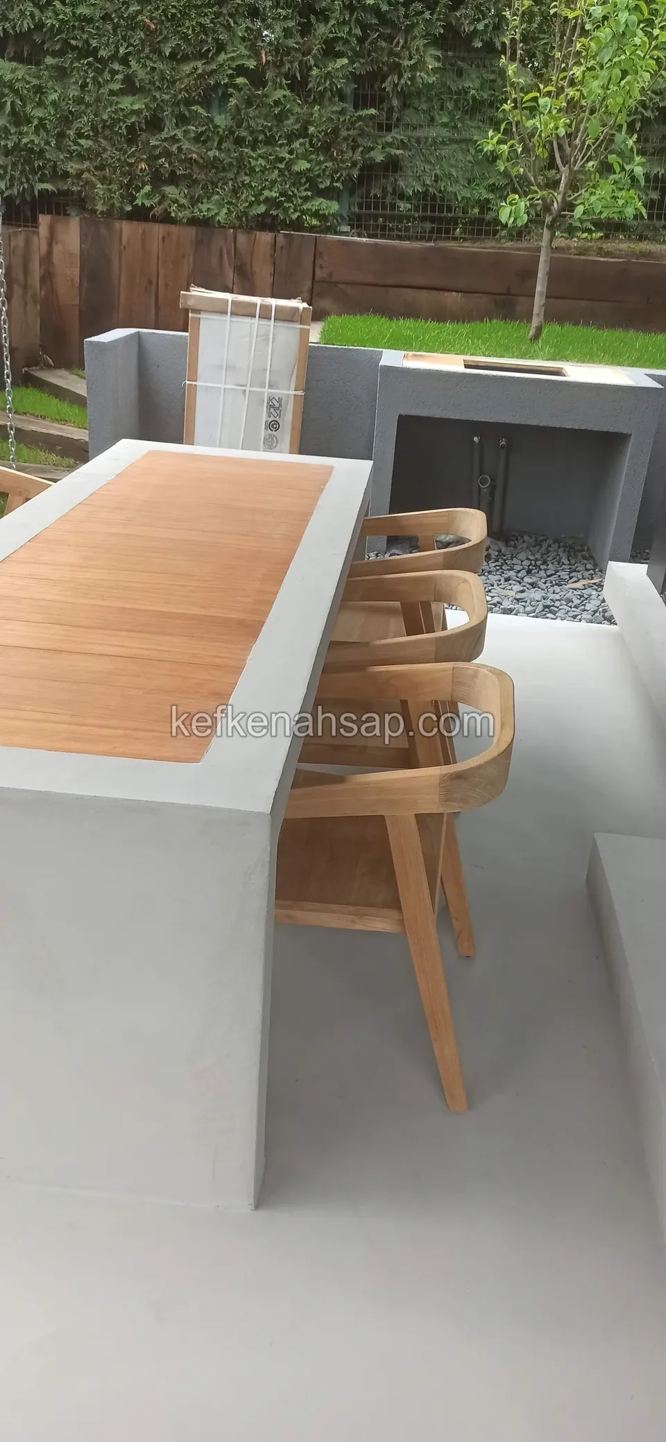 Beton tezgâhın üstünde ahşap çıtalı yüzey; tezgâhın yanında ahşap sandalyeler duruyor
