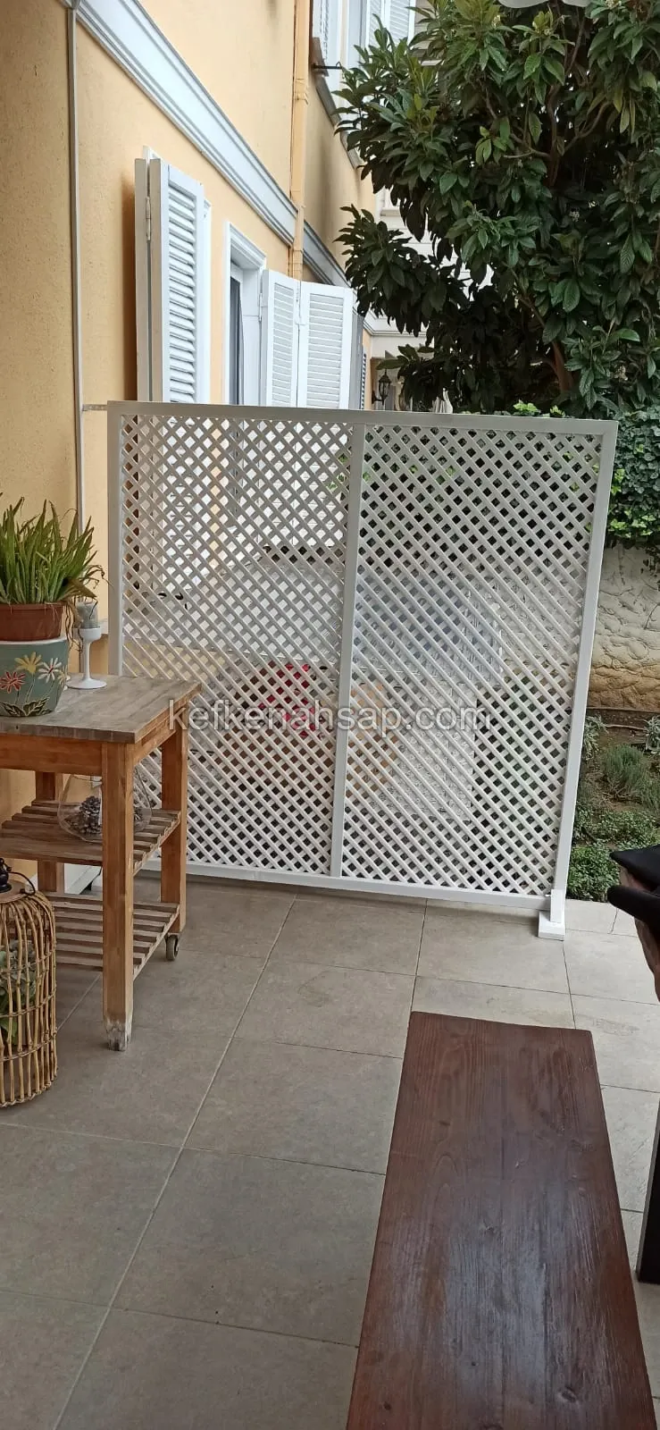 حاجز خشبي أبيض بقضبان متقاطعة موضوع على أرضية فيراندا