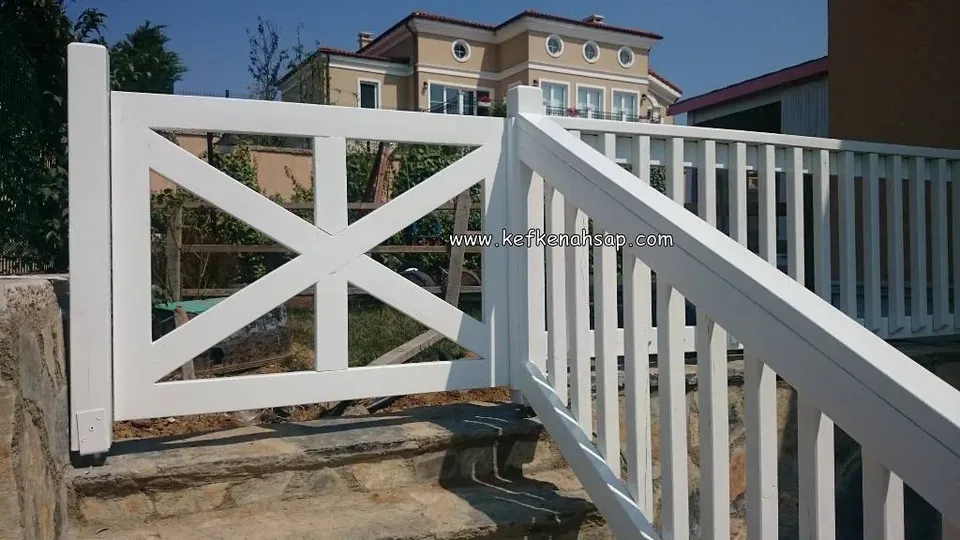 Taş merdiven kenarında beyaz ahşap tırabzan korkuluğu ve çapraz desenli ahşap güvenlik kapısı.