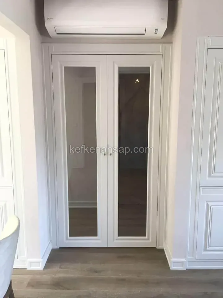 Duvar içine yerleştirilmiş, beyaz boyalı çıtalı çerçeveye sahip, uzun cam panelli çift kanatlı kapı; üstünde klima var