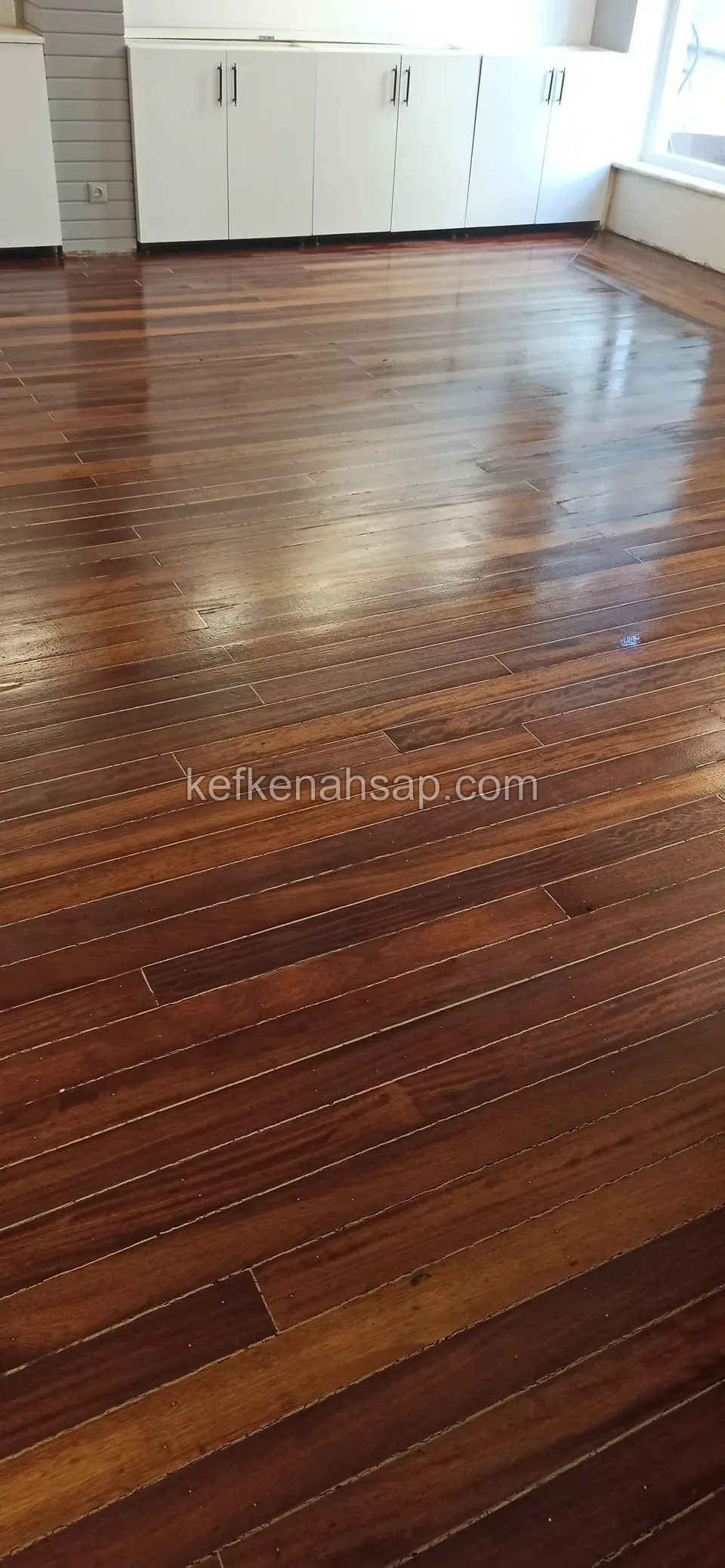 Beyaz dolaplı odada parlak vernikli koyu kahverengi ahşap parke zemini