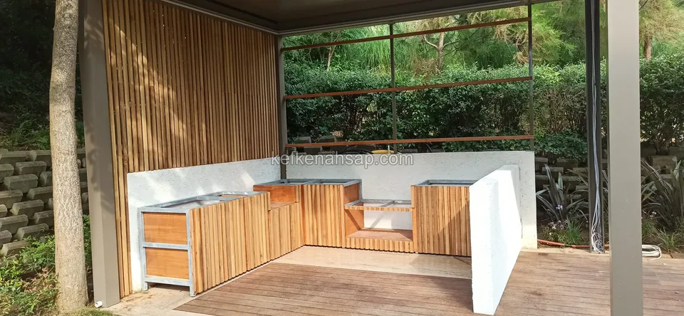 Holzverkleidete Außenküchenschränke in U-Form vor einer weißen Wand auf einem Deck