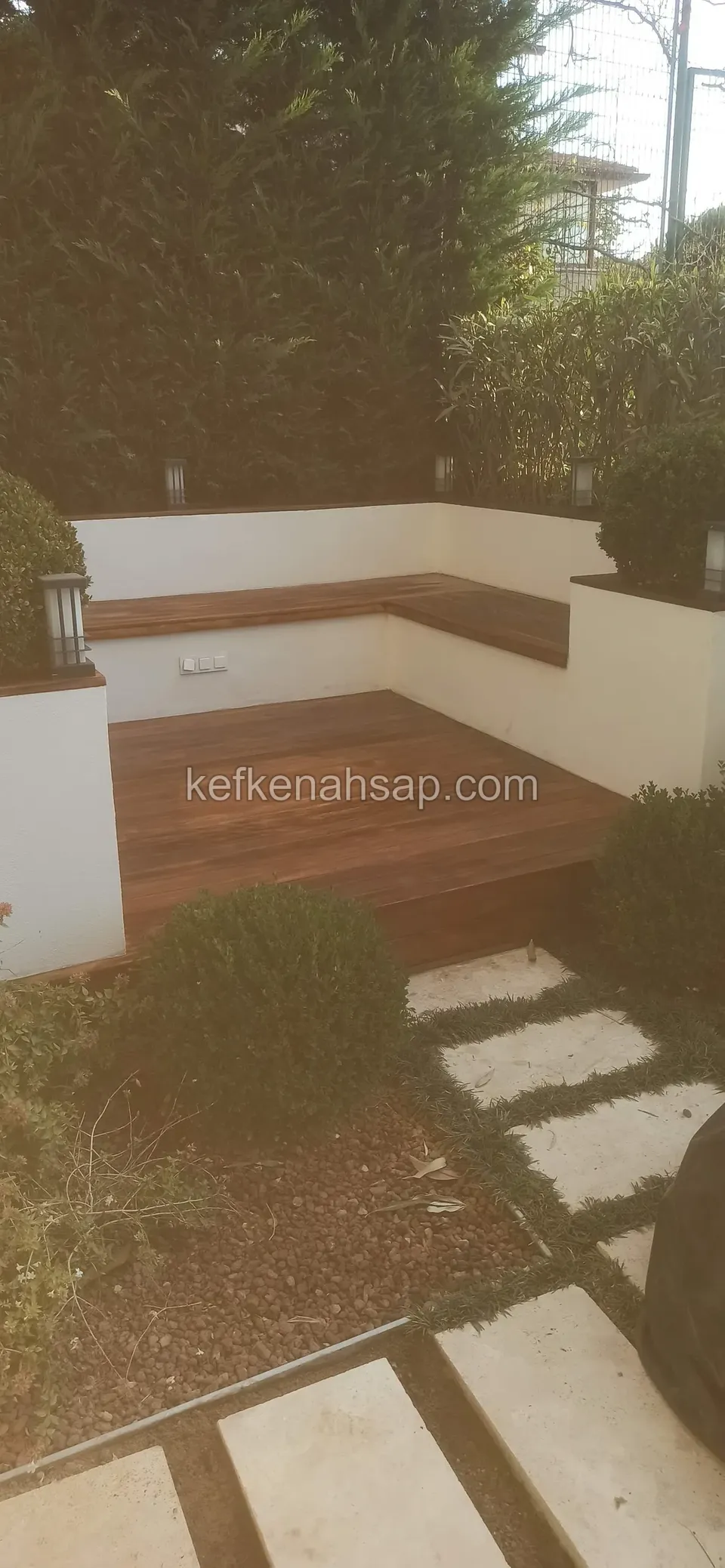 A corner timber bench set in white-rendered walls with a dark brown deck floor