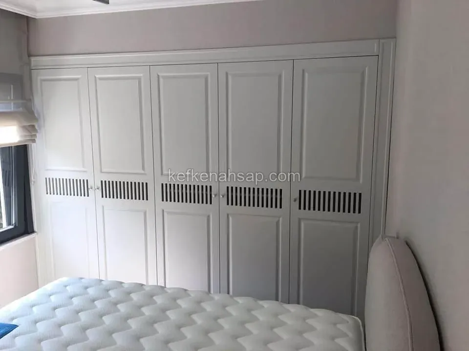 Yatak odasına tam boy gömme yapılan, orta kısmı ızgara çıtalı beyaz lake gardırop kapakları.
