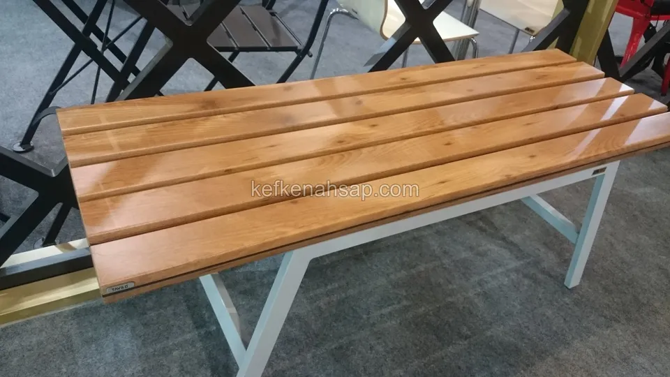 Beyaz metal ayaklar üzerinde duran, parlak vernikli çıtalı ahşap bank