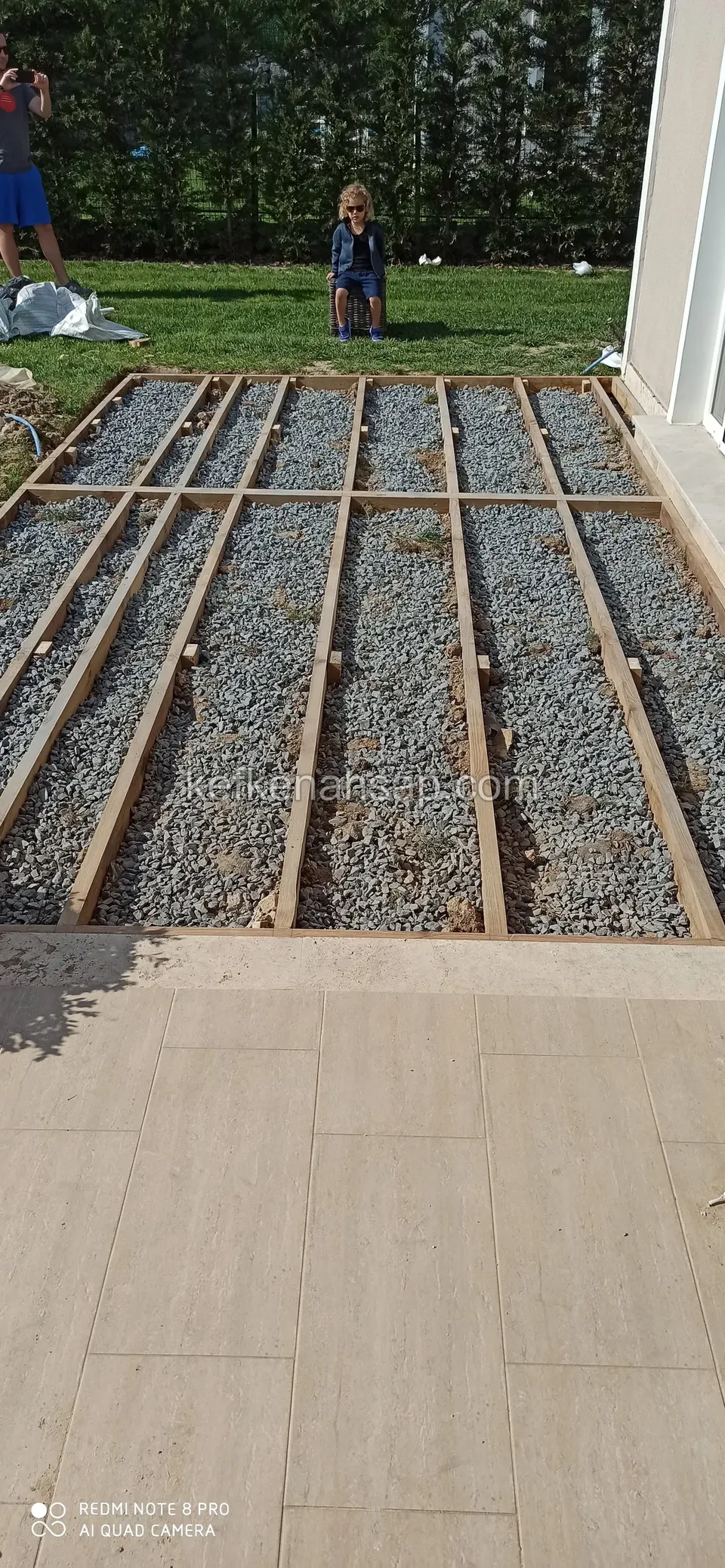 Timber deck joists in a gravel-filled area in front of the house, next to ceramic flooring