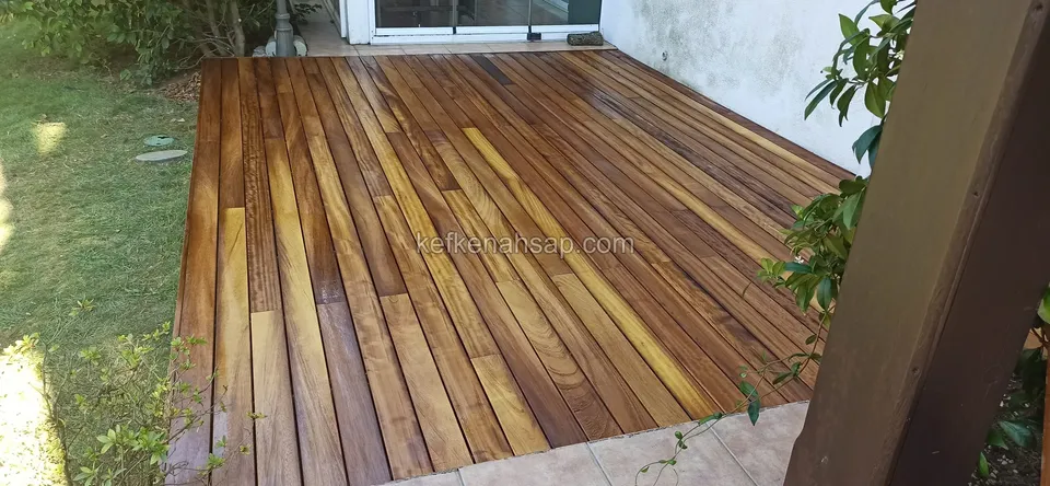 Polished deck boards in tones from yellow to dark brown, running out from a glass sliding door