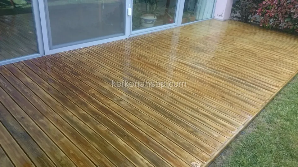 Honey-coloured deck with a glossy light-reflecting surface along ground-floor sliding glass doors, lawn beside it