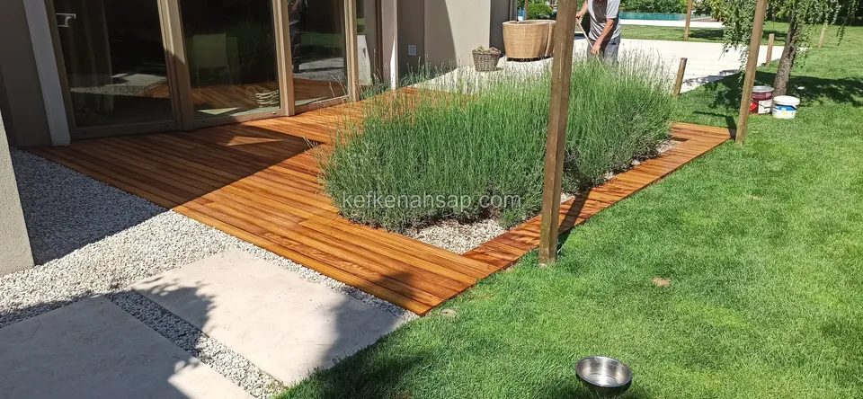 Cam kapılı binanın önünde lavanta etrafında dolanan turuncu deck; uzakta bir kişi, yerde metal kap