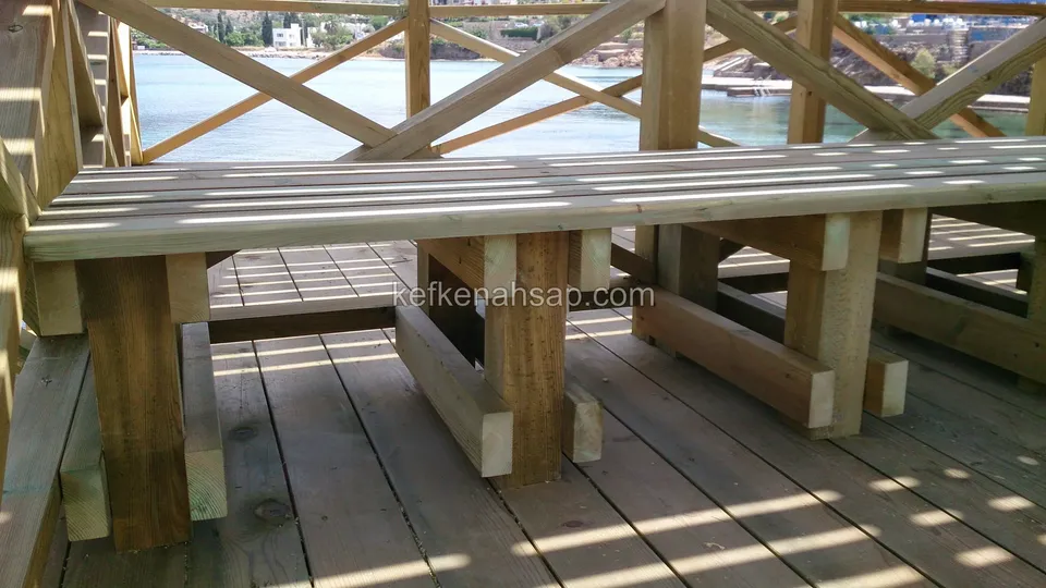 Auf einem Holzdeck zum Wasser hin, vor einem Kreuzgeländer