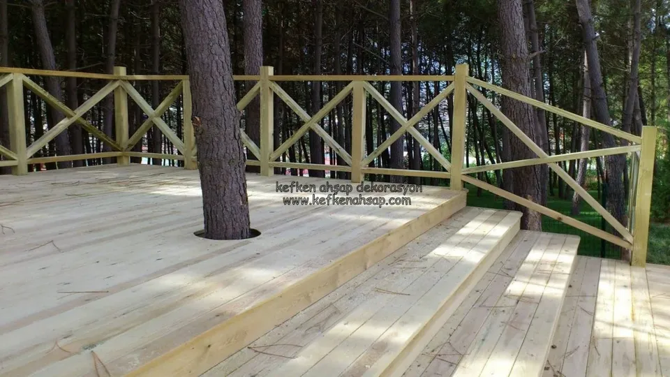 Çam ormanında basamaklı ahşap deck, gövdesi zeminden geçen ağaç ve çapraz çıtalı ahşap korkuluk