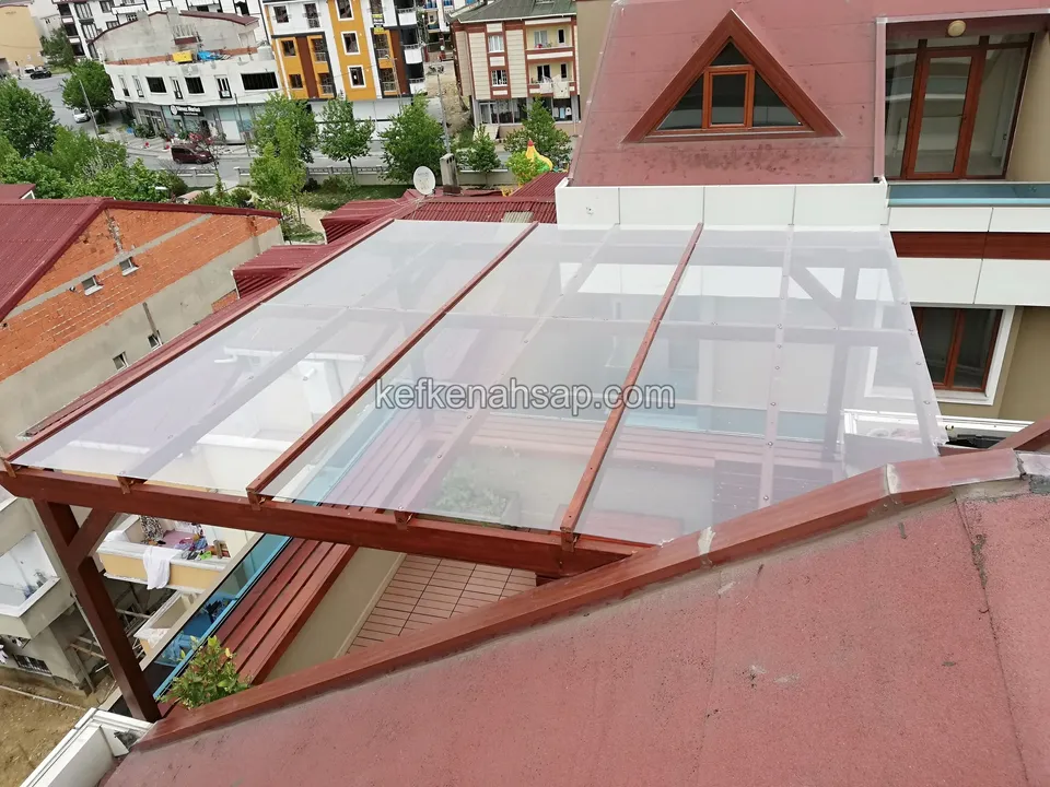 Dachterrassen-Pergola aus lasiertem Holz mit klaren Dachplatten von oben gesehen, ringsum Wohnblöcke