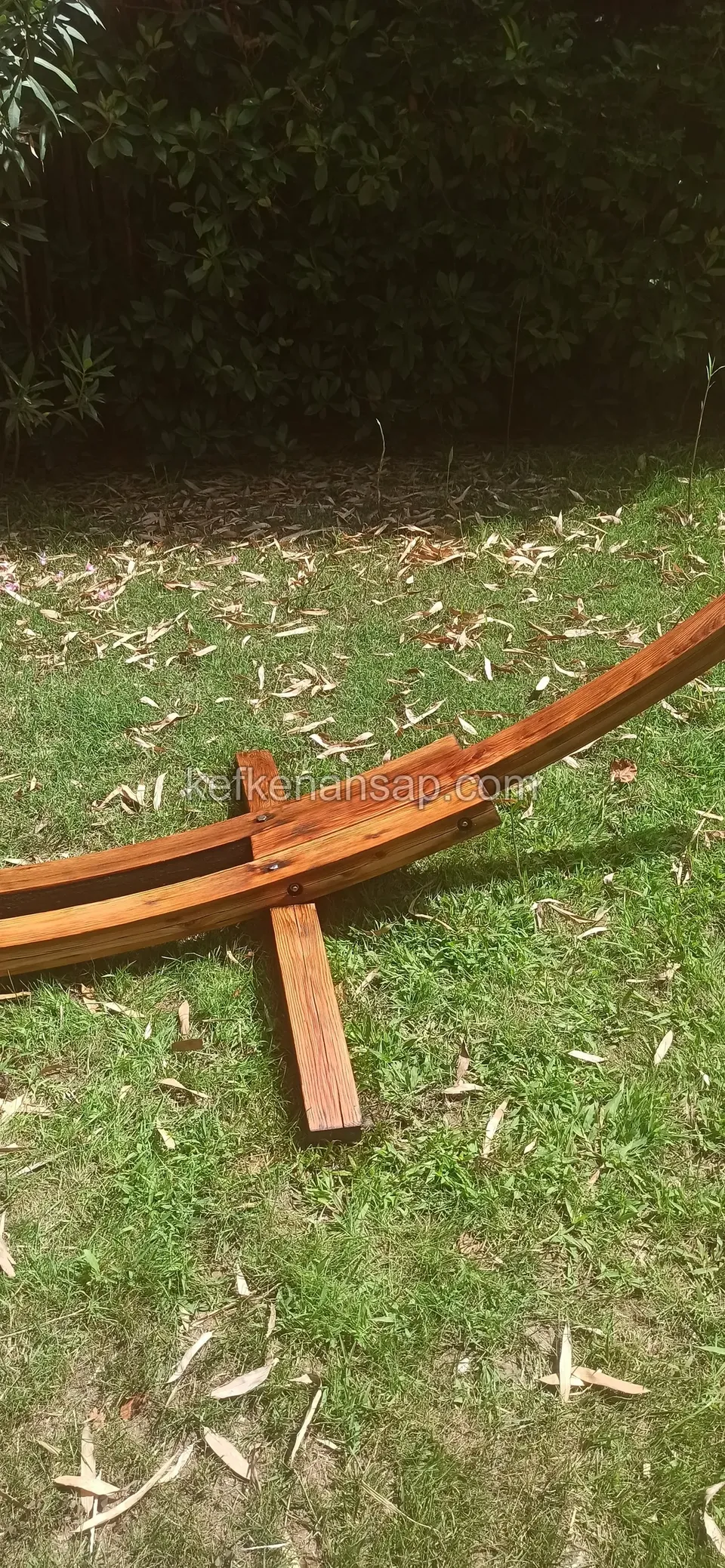 Curved timber arch and cross-foot piece lying on the grass