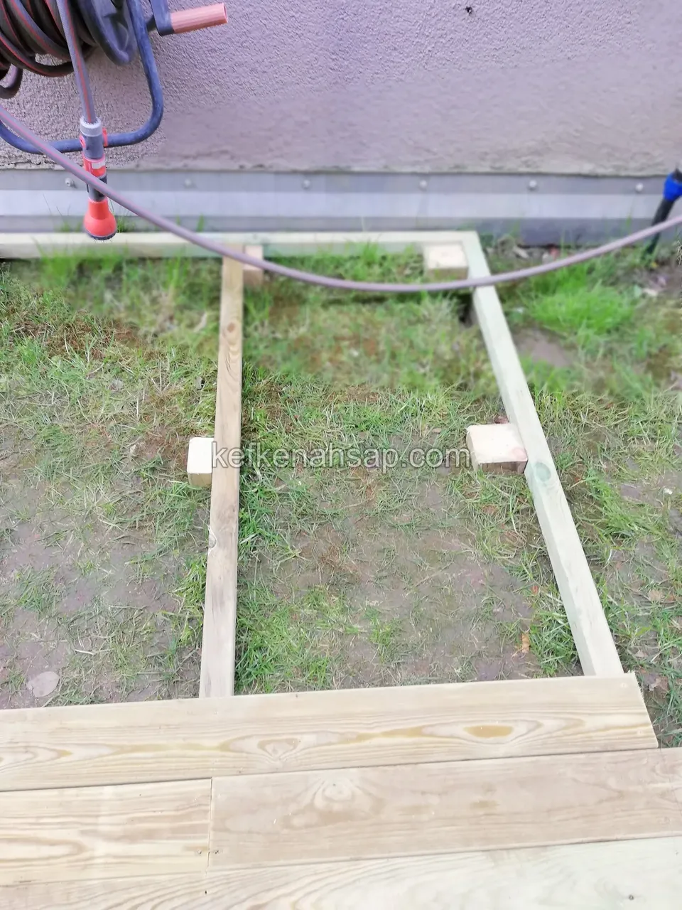 Timber deck joist frame on the lawn with the first new deck boards starting at the bottom
