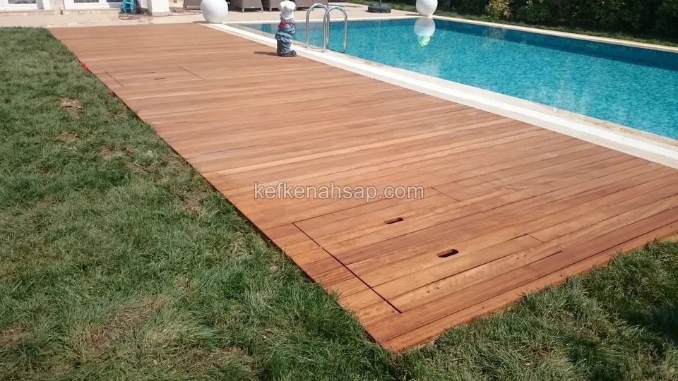 Havuzun yanında çimenle çevrili geniş deck yüzeyi, köşede kare bir bakım kapağı