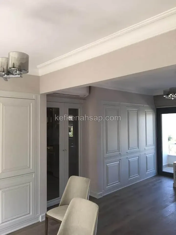 Graue Einbauschränke mit Lattentüren im Wohnzimmer, zweiflügelige Glastür, Deckenleiste und dunkler Parkettboden