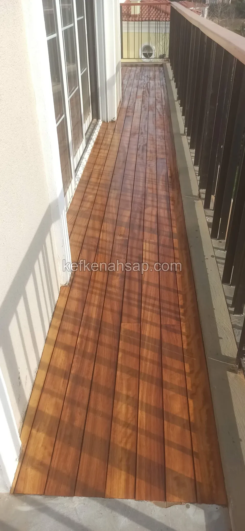 Glossy orange-brown polished deck covering a long narrow balcony, with a timber railing alongside