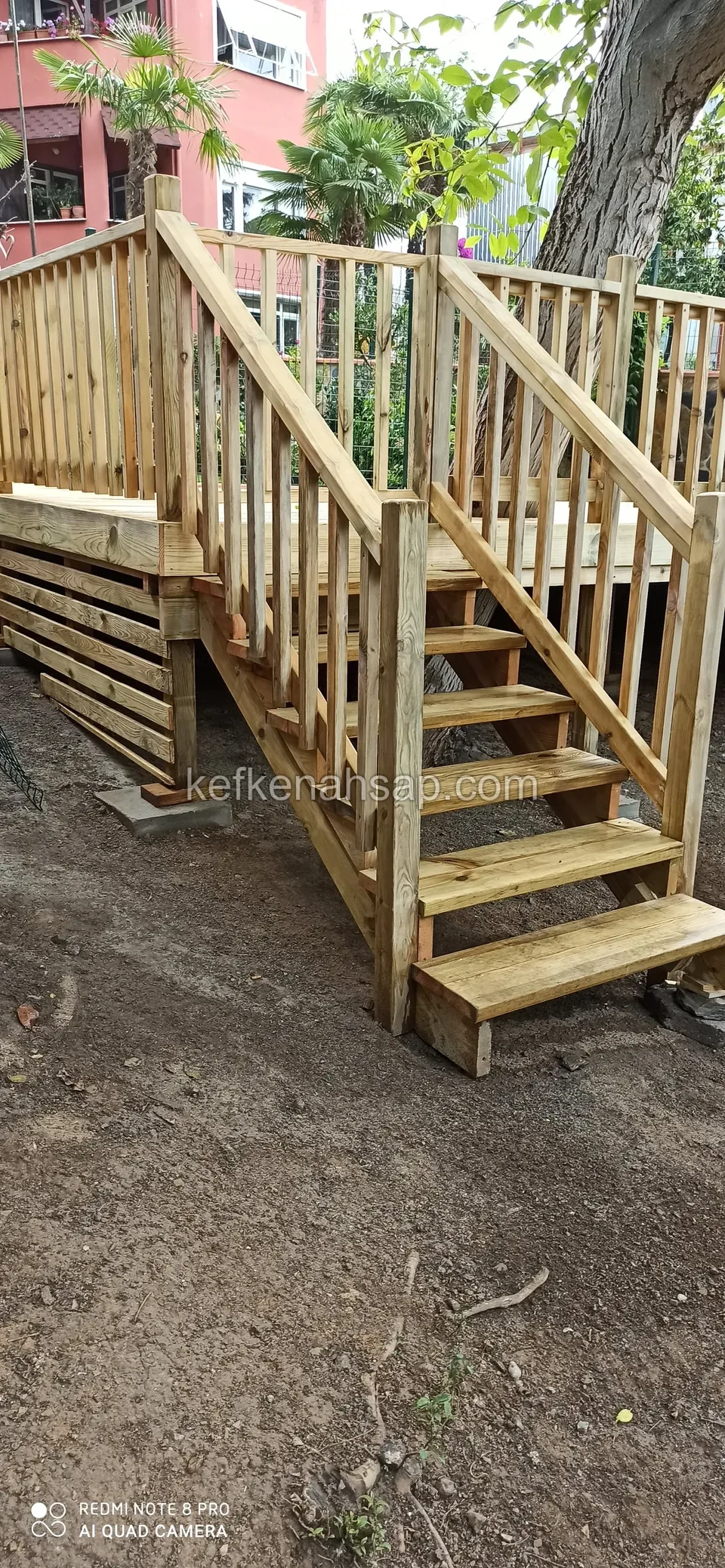 Yükseltilmiş deck platformuna çıkan, dikey çıtalı korkuluklu açık renkli ahşap merdiven