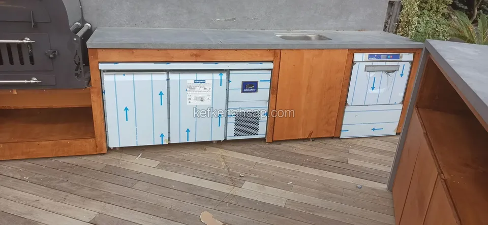 Außenküchenzeile auf einem Holzdeck, gebaut mit Holzschränken und Einbaugeräten