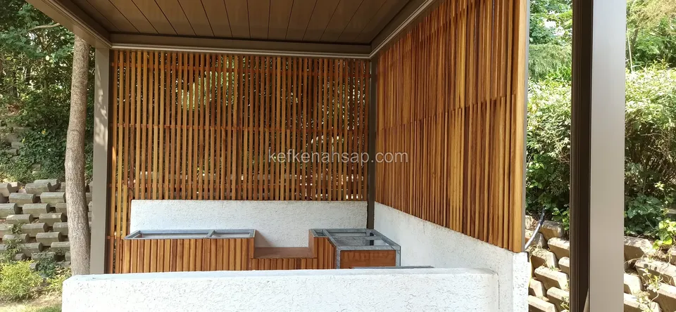 Niedrige holzverkleidete Schränke vor einer weißen Wand am Fuß einer senkrechten Holzlattenwand