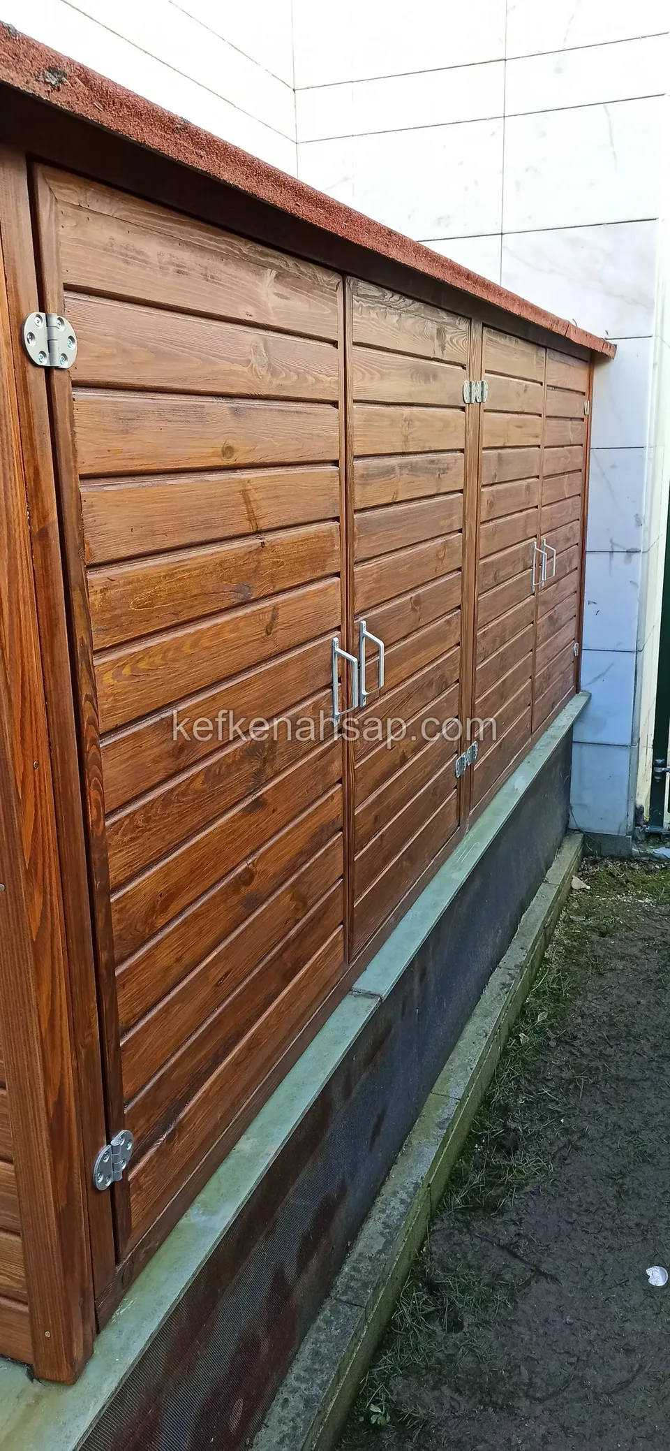 Holzschrank mit waagerechten Brettertüren und Metallscharnieren entlang einer Gebäudewand
