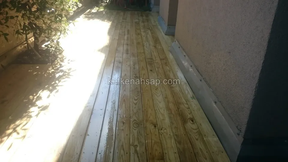 Close-up of wet, shining timber deck boards beside a wall