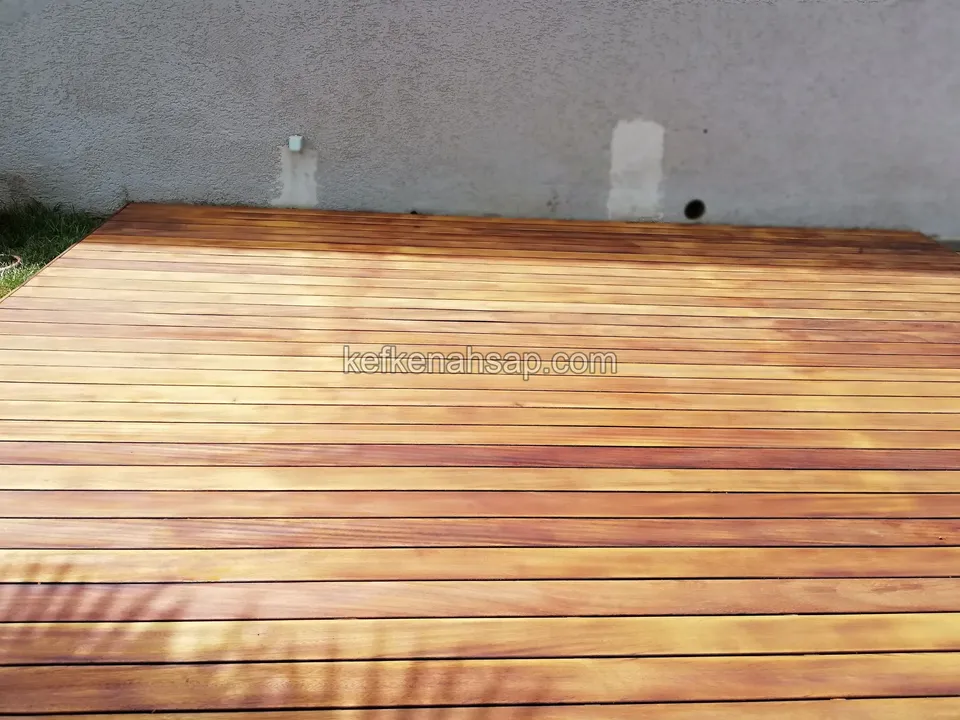 Lackierter orangebrauner Holzterrassenboden vor einer grauen Wand