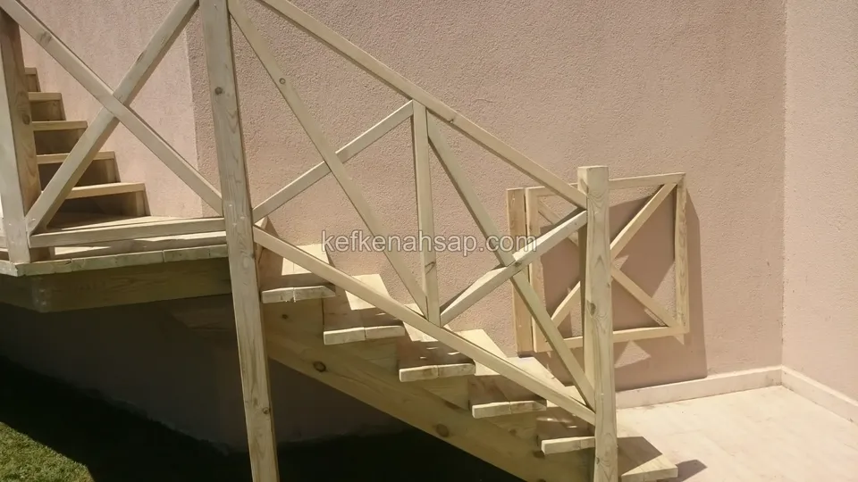 Pembe duvar yanında platform, basamaklar ve çaprazlı korkuluk; köşede kısa bir korkuluk parçası