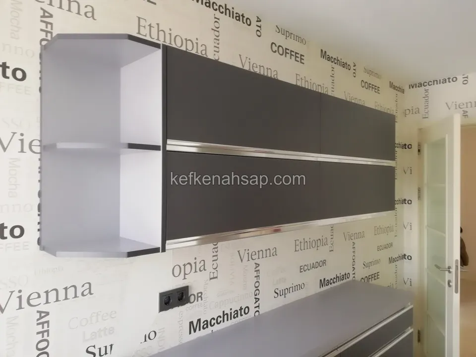 Duvara monteli, iç yüzü beyaz, kapakları koyu gri ve kenarı metal profilli üst dolap modülü; solda açık raf