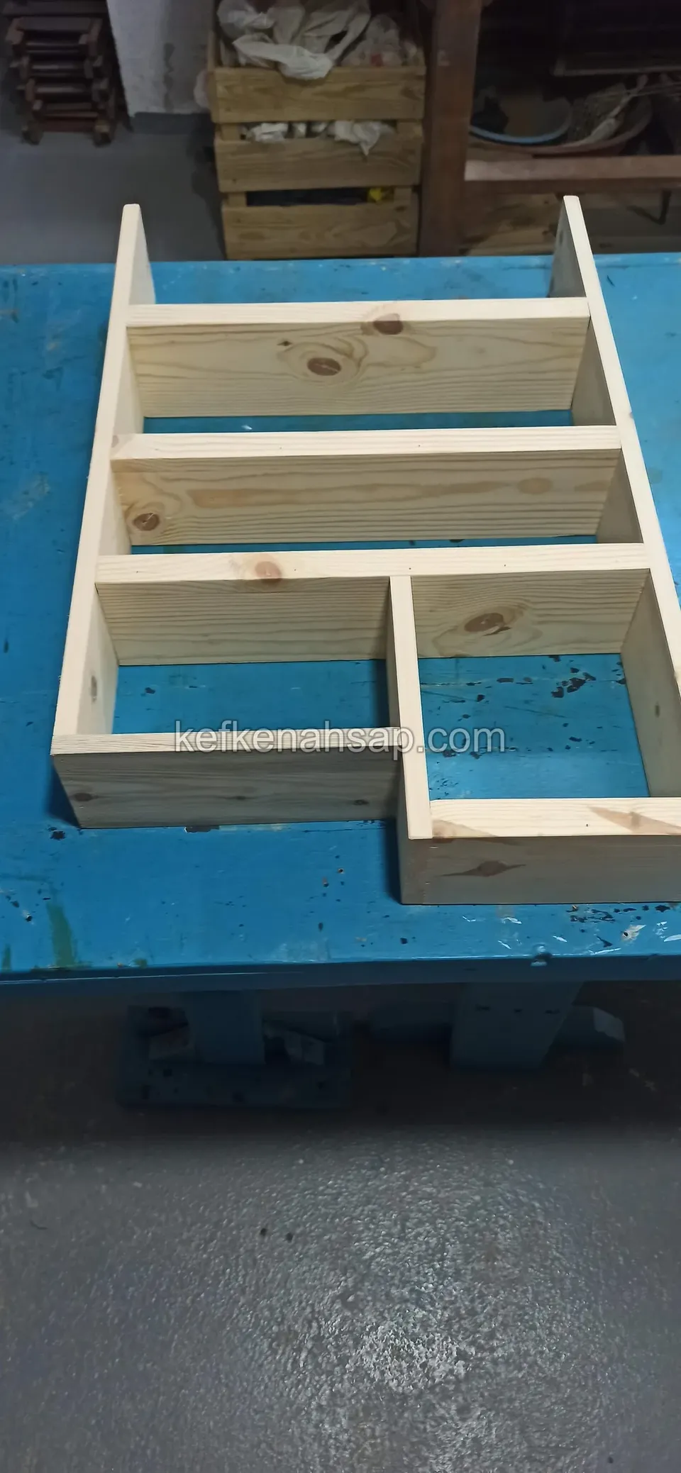 Ein stufenförmiger Holzregalkorpus aufrecht auf einer Werkbank, mit Fächern unterschiedlicher Größe