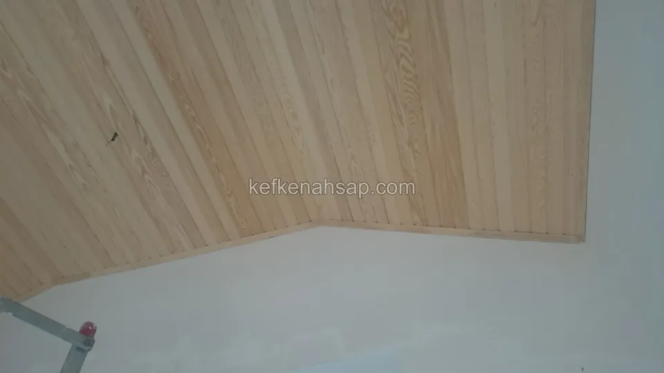Köşede kırılan eğimli lambri tavan, altta çıplak alçı duvar ve solda iskele parçaları