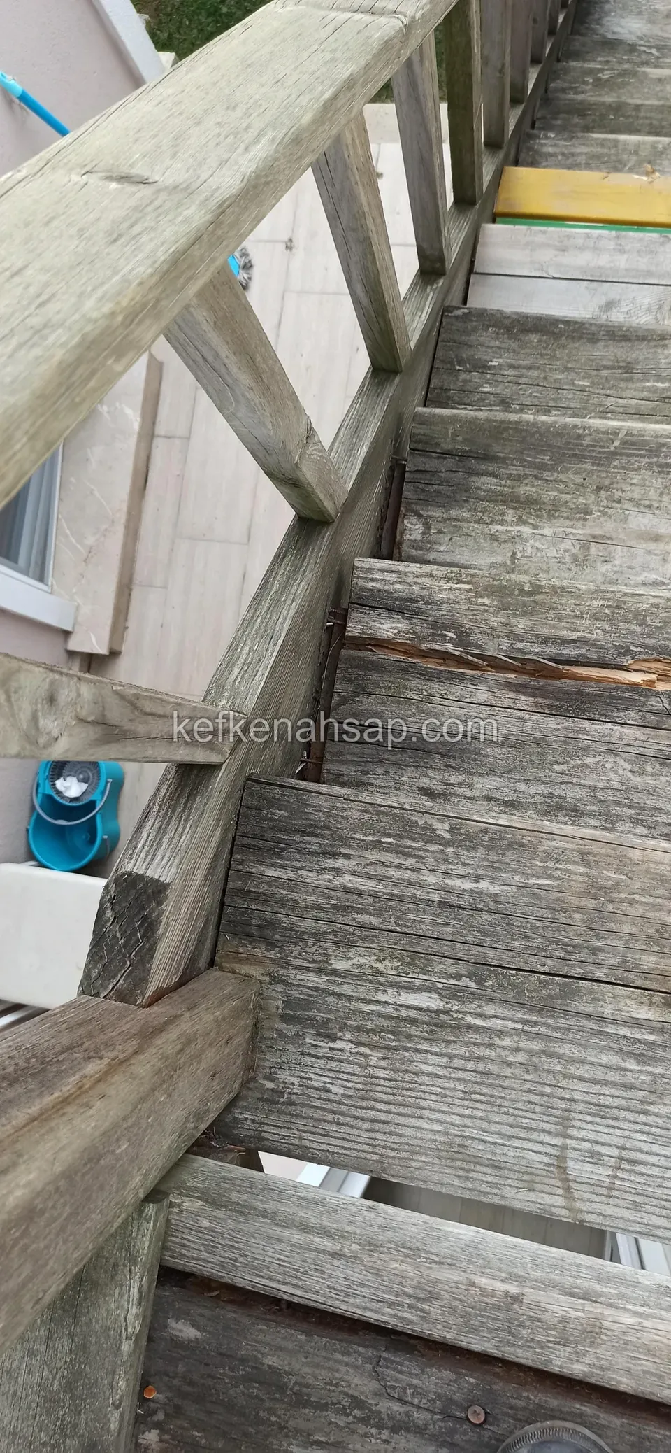Eski gri ahşap merdivenin basamakları ve çapraz çıtalı korkuluğu, yukarıdan çekim