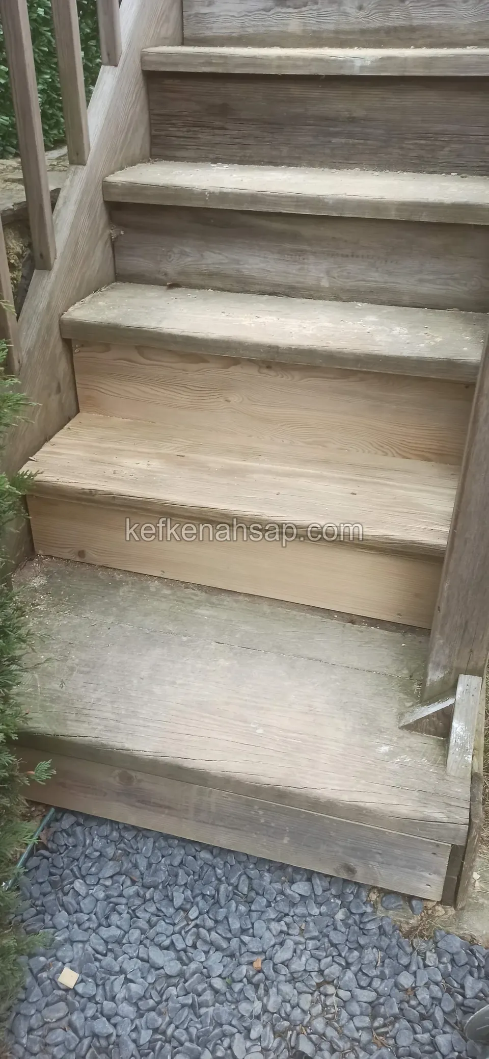 Eskimiş, grileşmiş ahşap basamaklar; alt kısımda çakıl zemin